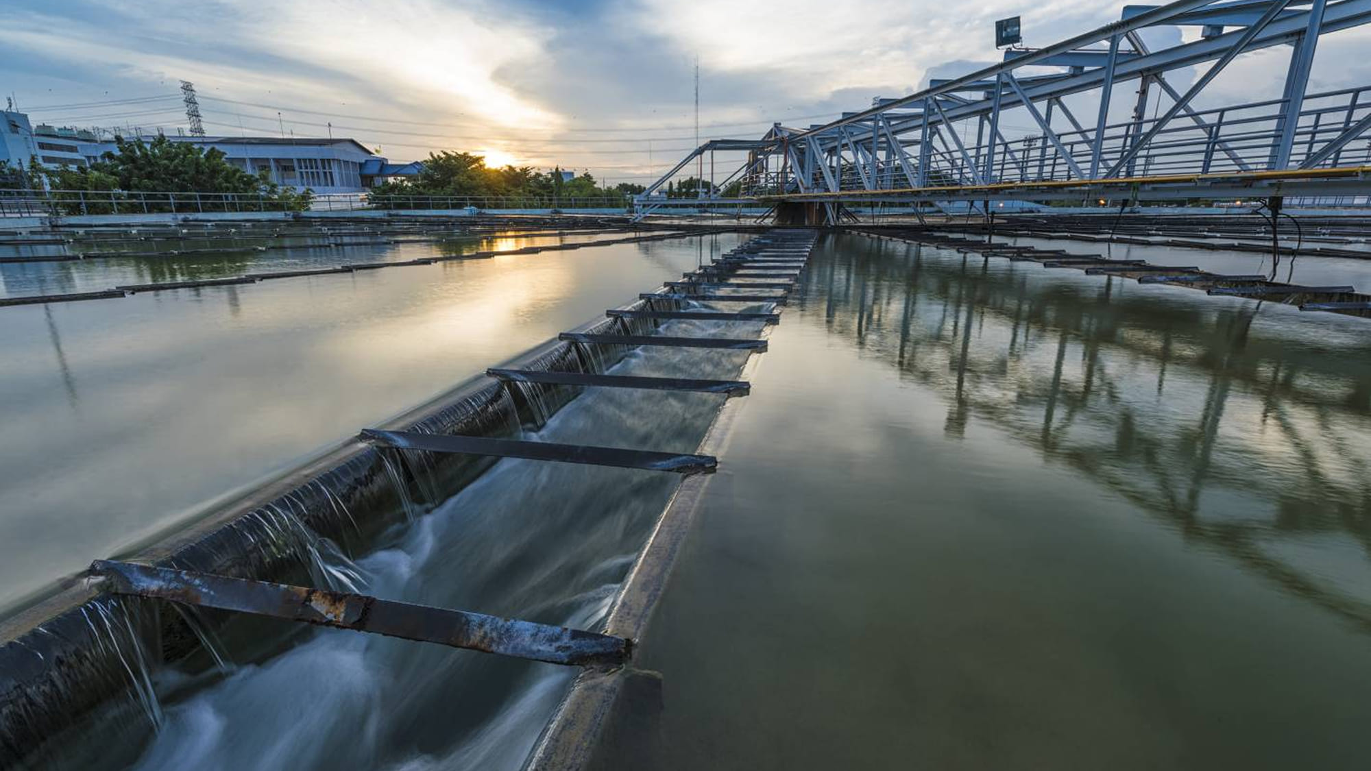 Water treatment plant at dusk, weir in the foreground